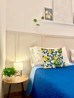 a bedroom with a blue bed and a table at Michelle Holiday House in Castellammare del Golfo