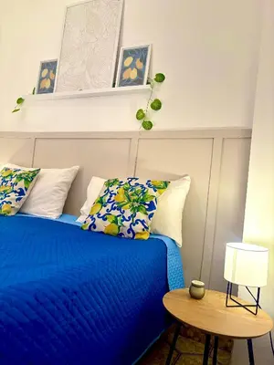 a bedroom with a blue bed with pillows and a table at Michelle Holiday House in Castellammare del Golfo