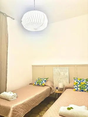 a room with two beds and a pendant light at Michelle Holiday House in Castellammare del Golfo