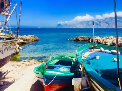 a green boat sitting on the beach next to the water at Suite Vicino al Mare in Carini