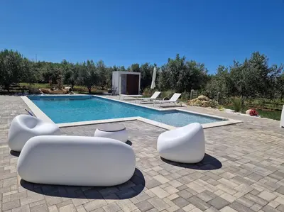 a swimming pool with some white chairs and aitureshiba at Villa Degli Ulivi in Partinico