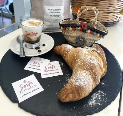 a table with a plate with a pastry and a cup of coffee at Soste Normanne in Palermo