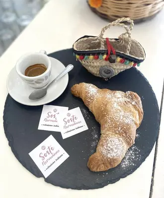 a black plate with a cup of coffee and a pastry at Soste Normanne in Palermo