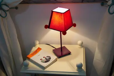 a table with a lamp and a book on it at My House Holiday Apartment in Palermo