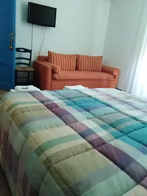 a bedroom with a bed with a couch in the background at B&B SoleLuna della Solidarietà in Palermo