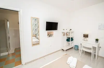 a white room with a desk and a tv on a wall at Central Room 128L in Palermo