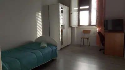 a bedroom with a bed and a tv and windows at La casetta della stazione in Palermo