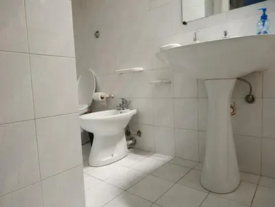a white bathroom with a sink and a toilet at La casetta della stazione in Palermo