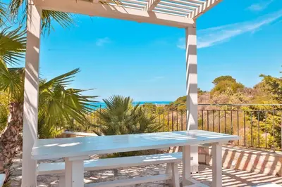 a white bench sitting on a balcony overlooking the ocean at Villa con Piscina 150mt dal Mare 8 Posti OA in Alcamo