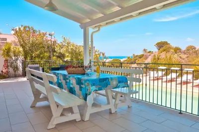 a table and chairs on a balcony with a view of the ocean at Villa con Piscina 150mt dal Mare 8 Posti OA in Alcamo
