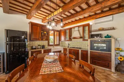 a kitchen with a wooden table and a dining room at Villa DelMarmo in Alcamo