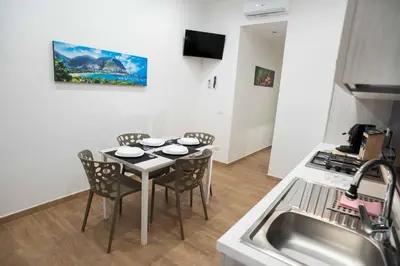 a kitchen with white cabinets and a table and a sink at Yris House in Palermo