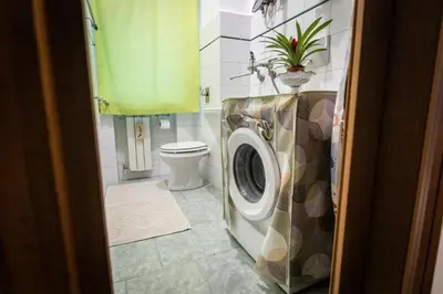 a bathroom with a toilet and a washing machine at Nanà Apartment in Palermo