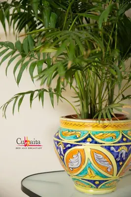 a colorful vase with a plant in it on a table at B&B Cubbaita in Palermo
