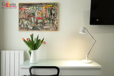 a desk with a lamp and a painting on the wall at B&B Cubbaita in Palermo