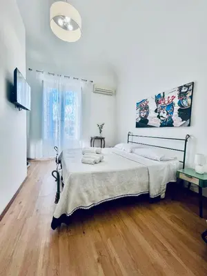 a white bedroom with a bed and a television at Mediterranea sole in Palermo
