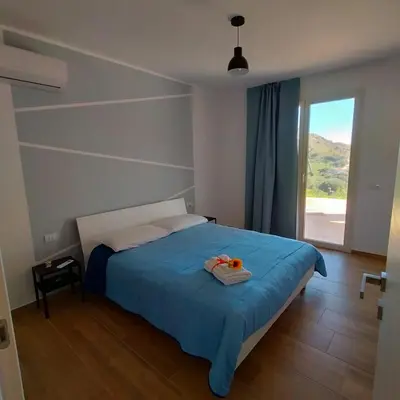 a bedroom with a bed with blue sheets and a window at Villa Saint George in Scopello