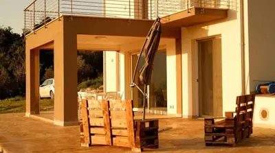 a patio with an umbrella and chairs in front of a house at Villa Saint George in Scopello