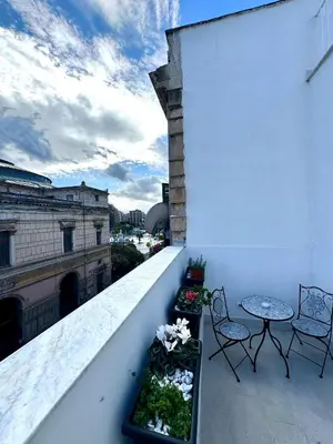 a balcony with two chairs and a table on a building at Politeama's Home - Luxury Apartment in Palermo