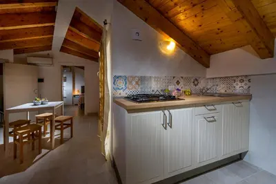 a kitchen with white cabinets and a table in a room at Affittacamere Amunì in Castellammare del Golfo