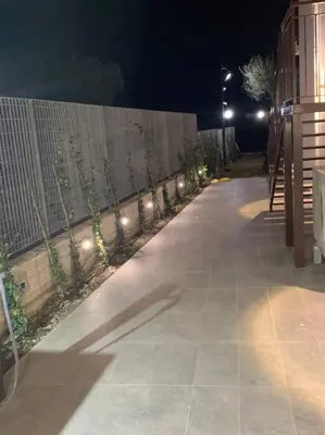 a sidewalk at night with a fence and lights at Trabia Casa Bianca A in Mandra Capreria