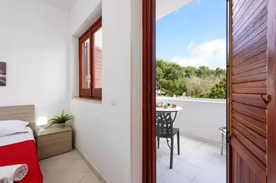 a bedroom with a bed and a balcony with a table at Casa Vacanze Margherita in San Vito lo Capo