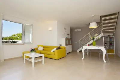 a living room with a yellow couch and a piano at Villa Bianca in Alcamo