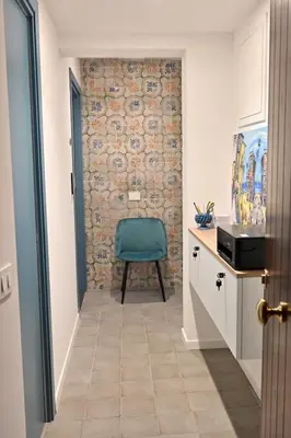 a hallway with a blue chair in front of a wall at Aria di Sale centro storico in Palermo