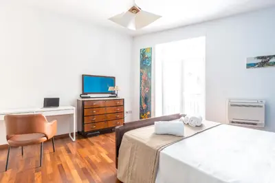 a bedroom with a bed and a tv and a chair at Piazza Marina Holiday House by DomuSicily in Palermo