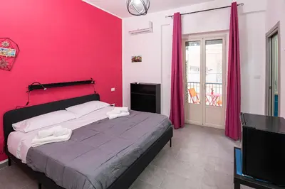 a bedroom with a bed with a pink wall at Splendori Rooms in Palermo