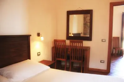 a bedroom with a bed and a desk and a mirror at Agriturismo Case Tabarani in Collesano