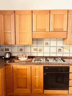 a kitchen with wooden cabinets and a black appliance at Casa Praiola in Terrasini