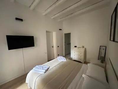 a white bedroom with a bed and a flat screen tv at La Dimora Del Centro in Palermo