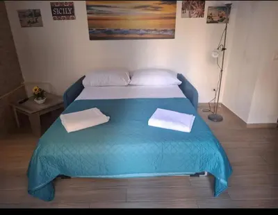 a blue bed with two towels on top of it at Sunflower Apartment in Palermo