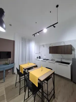 two tables in a kitchen with yellow tables and chairs at Donna Rosa House in Palermo