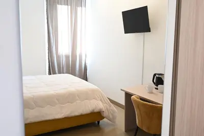 a bedroom with a bed and a desk with a television at Manno's Apartment in Palermo