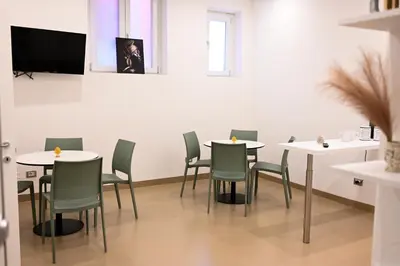 a dining room with white tables and green chairs at Manno's Apartment in Palermo