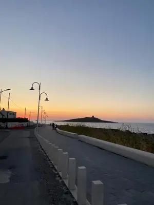 a street with street lights and the ocean at sunset at Finestra del mare in Isola delle Femmine