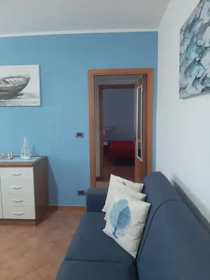 a blue living room with a blue couch and a table at Residence Le Perle Beach in San Vito lo Capo