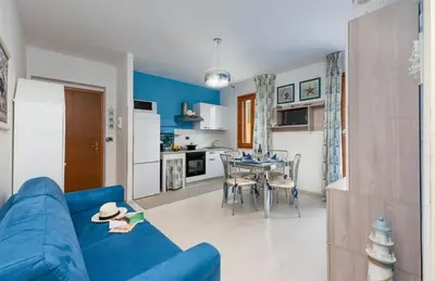 a living room with a blue couch and a table at Residence Le Perle Beach in San Vito lo Capo
