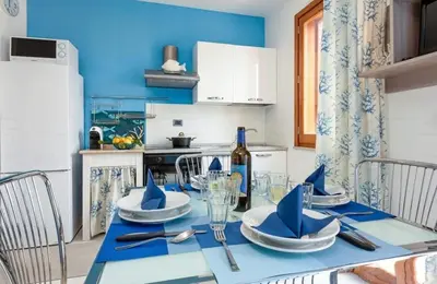 a kitchen with a table with a bottle of wine at Residence Le Perle Beach in San Vito lo Capo