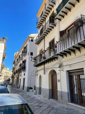 a white building with balconies and a street with cars at #Secretplace in Palermo