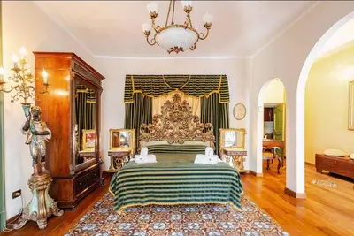 a bedroom with a large bed with a chandelier at Palazzo Viola Suite Panoramica Palermo in Palermo
