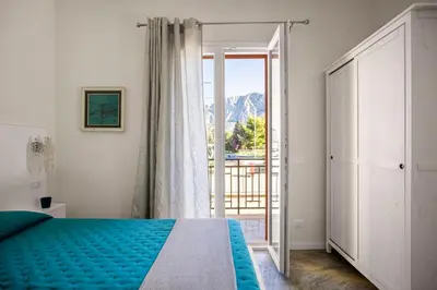 a bedroom with a bed and a door to a balcony at La casetta di Levante in Terrasini