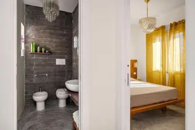a bedroom with a bed and a toilet and a sink at La casetta di Levante in Terrasini