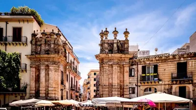 an old building with tables and umbrellas in a city at Tra i Vicoli del Capo in Palermo