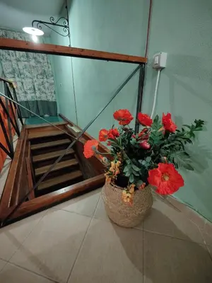 a vase with red flowers sitting next to a staircase at La Muciara - Best Hospitality in Palermo