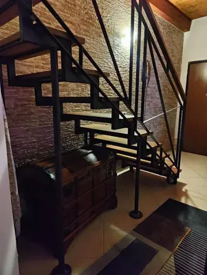 a black spiral staircase in a room with a brick wall at La Muciara - Best Hospitality in Palermo