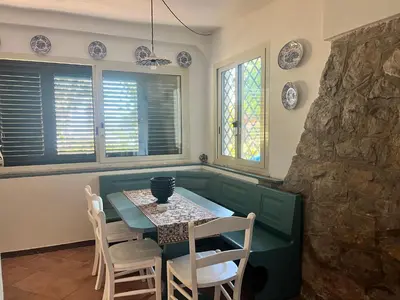 a dining room with a table and chairs and windows at Casa sul mare Lalu a 20 kl da Palermo e 30 da Cefalu tre camere 9 posti in Santa Flavia