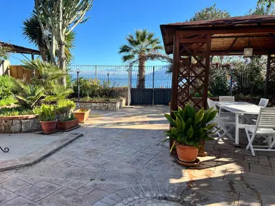 a patio with a table and chairs and the ocean at Casa sul mare Lalu a 20 kl da Palermo e 30 da Cefalu tre camere 9 posti in Santa Flavia